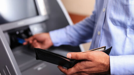 man pulling card out of wallet and inserting it into atm